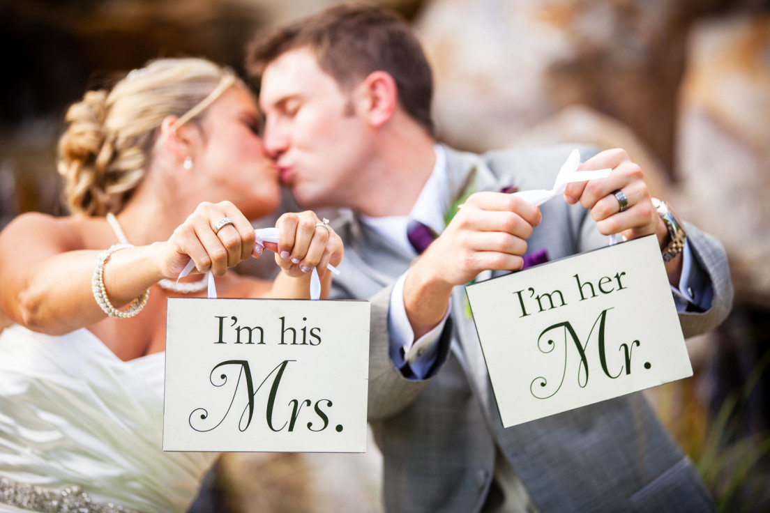 Bride and groom kissing and holding signs